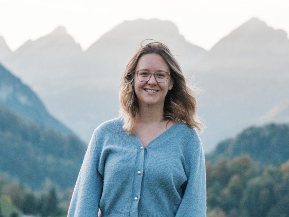 Elena Kuriger lächelnd vor den Bergen im Toggenburg